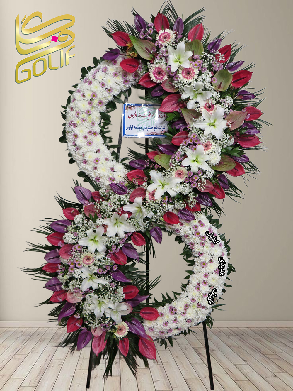 تاج گل تبریک دو طبقه (لیلیوم، تولیت، داوودی) گل‌های اصلی و غالب این تاج گل شامل موارد زیر هستند: لیلیوم سفید: به عنوان گل اصلی که در طراحی مرکز این تاج گل و شکل عدد ۸ دیده می‌شود. تولیت‌های صورتی و بنفش: که در ترکیب رنگ‌ها و هماهنگی زیبای گل‌ها برجسته هستند. داوودی‌های سفید و صورتی: به‌طور پراکنده در قسمت‌های مختلف تاج گل. این ترکیب گل‌ها به همراه طراحی هنری و لایه‌بندی خاص به تاج گل جذابیت و شکوه خاصی بخشیده‌اند. تاج گل افتتاحیه، تاج گل نمایشگاهی، تاج گل عقد و عروسی سفارش آنلاین تاج گل